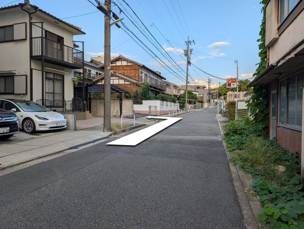 道路から見た駐車場入口。矢印で入る場所を示している